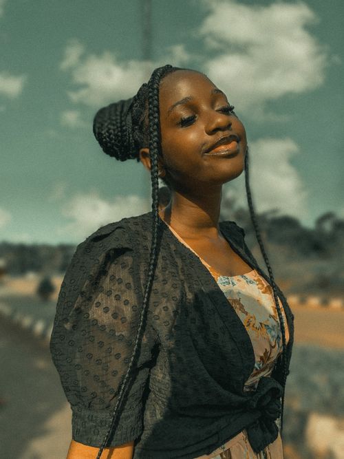 Free A woman poses confidently outdoors in Nigeria with eyes closed and braided hair. Stock Photo