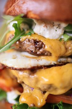 Mouthwatering close-up of a beef burger with melted cheese and fresh toppings.