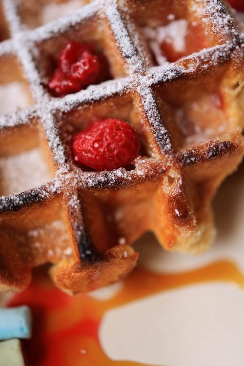 Free Close up of a waffle topped with red raspberries and syrup, sprinkled with powdered sugar. Stock Photo
