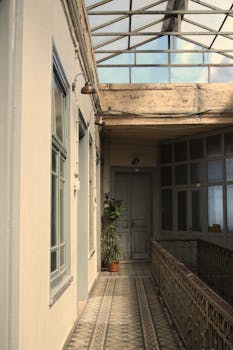 A vintage indoor corridor with a glass ceiling in an urban residential building.