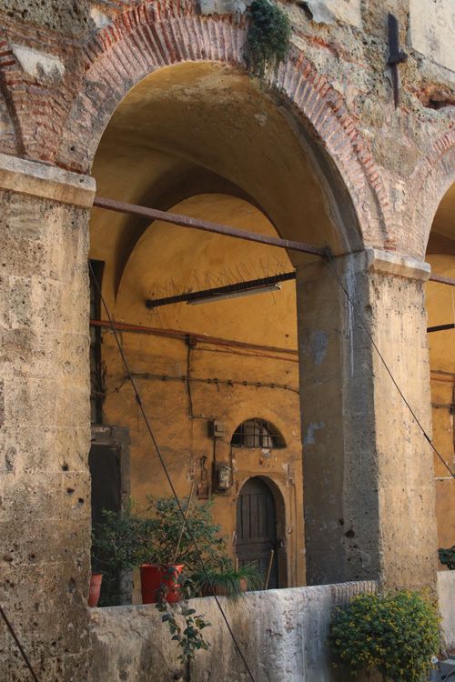 Free A captivating view of vintage stone arches with plants in a residential setting. Stock Photo