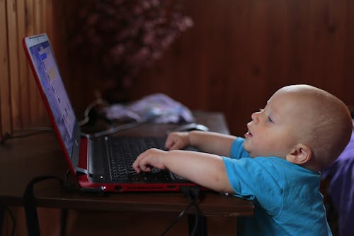Junge, Der Blaues T Shirt Mit Schwarzem Laptop Computer In Einem Schwach Beleuchteten Szenario Trägt