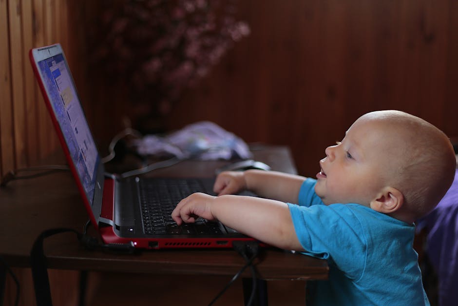 Boy Wearing Blue T Shirt Using Black Laptop Computer in a Dim Lighted Scenario