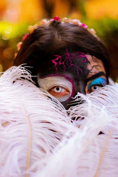 Portrait of Woman Wearing Spooky Makeup, Hiding Behind Feathers