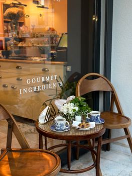 Charming outdoor cafe with coffee cups, cookies, and a floral setting perfect for a relaxing break.