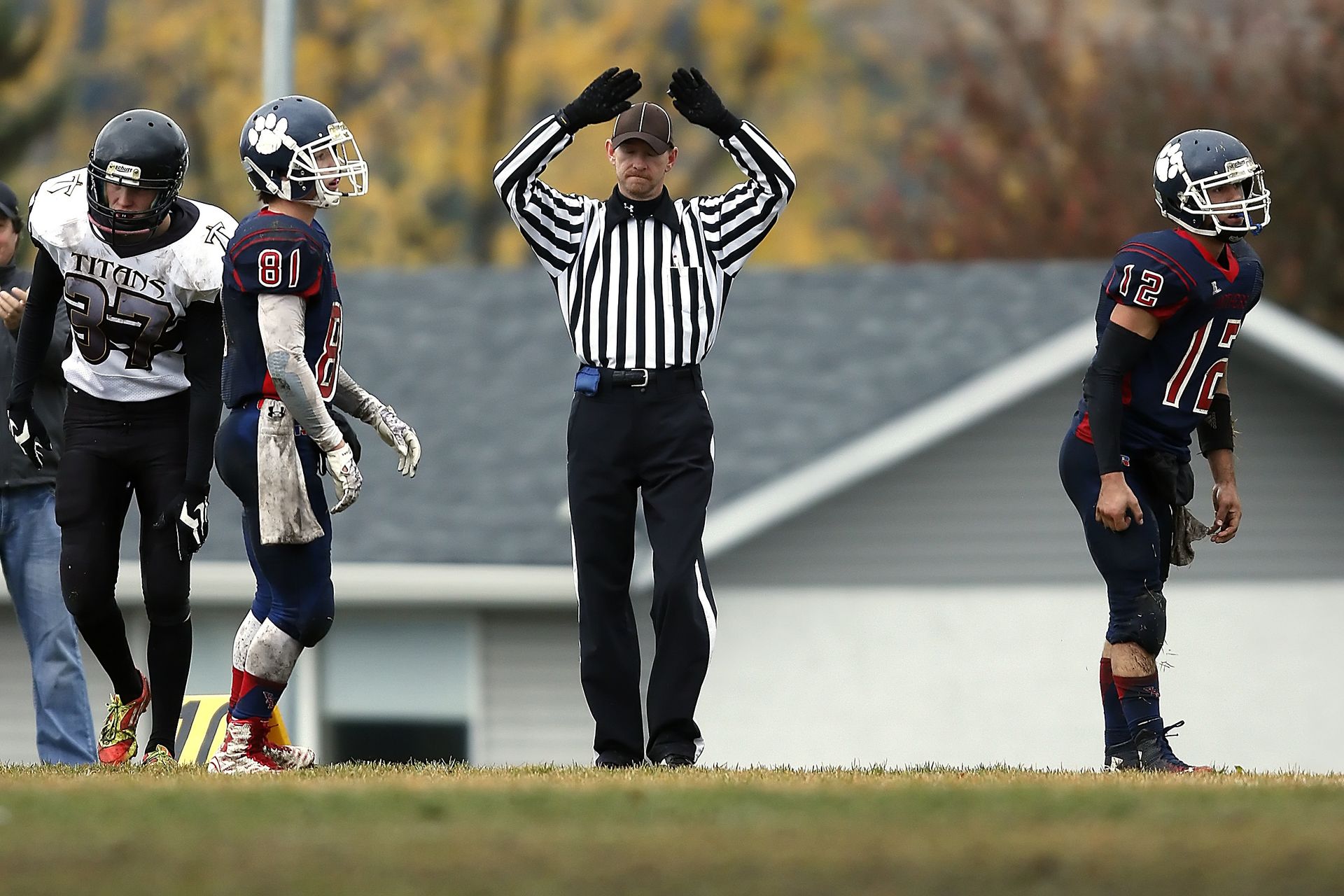 Referee calls timeout during intense high school football game outdoors.