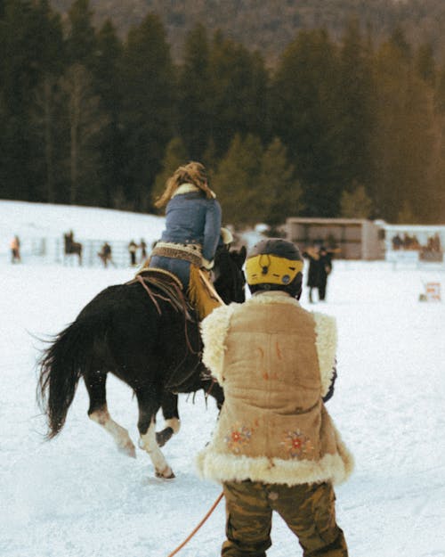 Woman Horseback Riding on a Snowy Ground in Mountains 