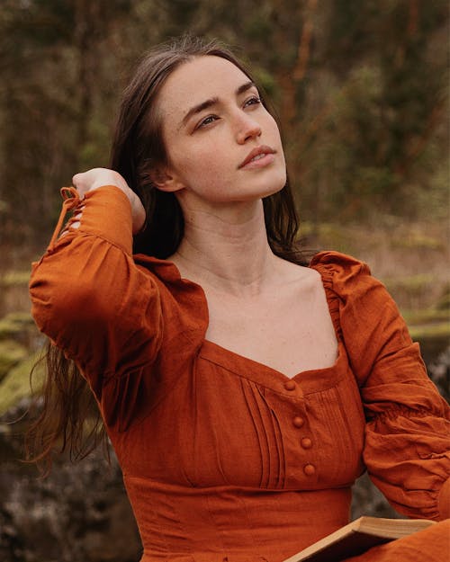 Woman in a Medieval Brown Dress Reading a Book in the Wild