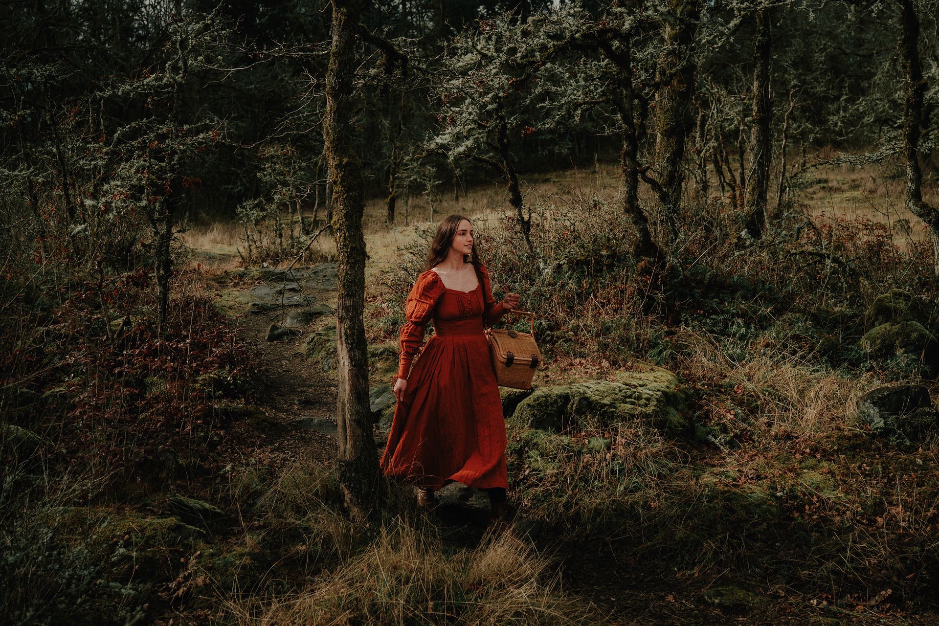 Woman in Red Medieval Dress Walking Through the Forest Carrying a Wicker Basket
