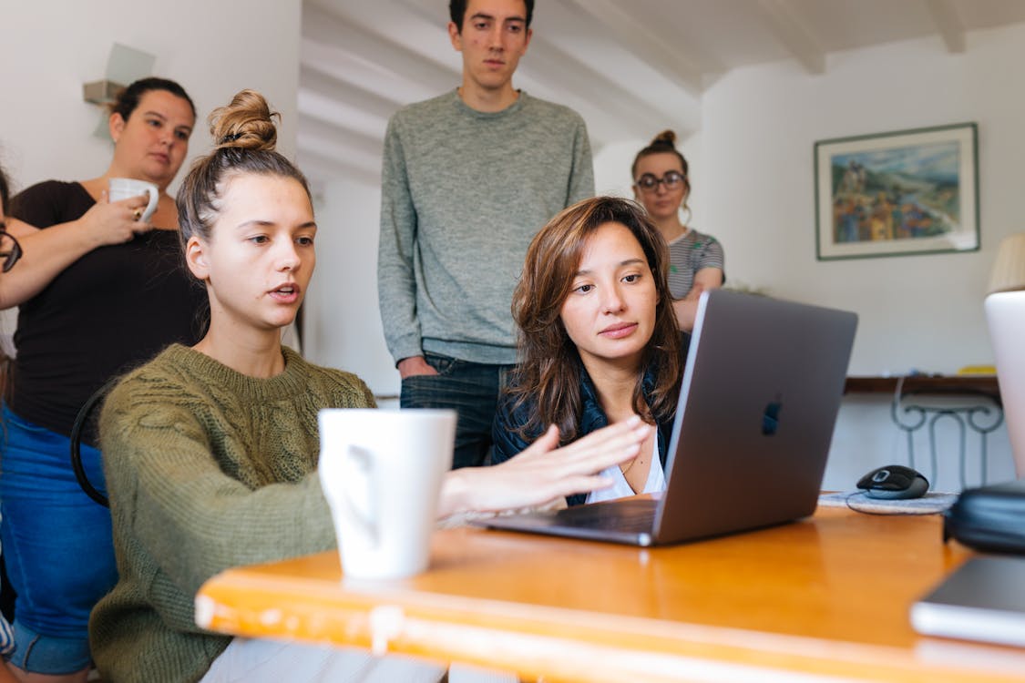 Free Woman In Green Top Using Macbook Beside Group Of People Stock Photo