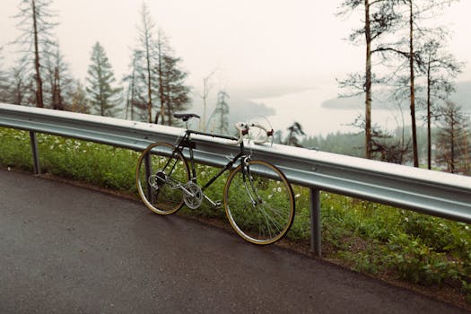 Vintage bicycle leaning on a guardrail with a foggy lake in the background, creating a serene landscape.