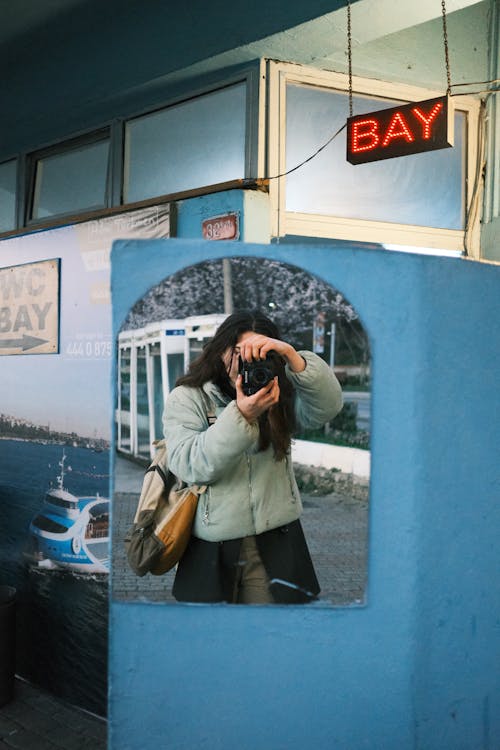 Woman Taking a Picture in a Mirror on the Street 