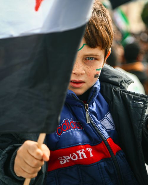 Free A young boy in Syria with a painted face holds a flag during a rally.  Stock Photo