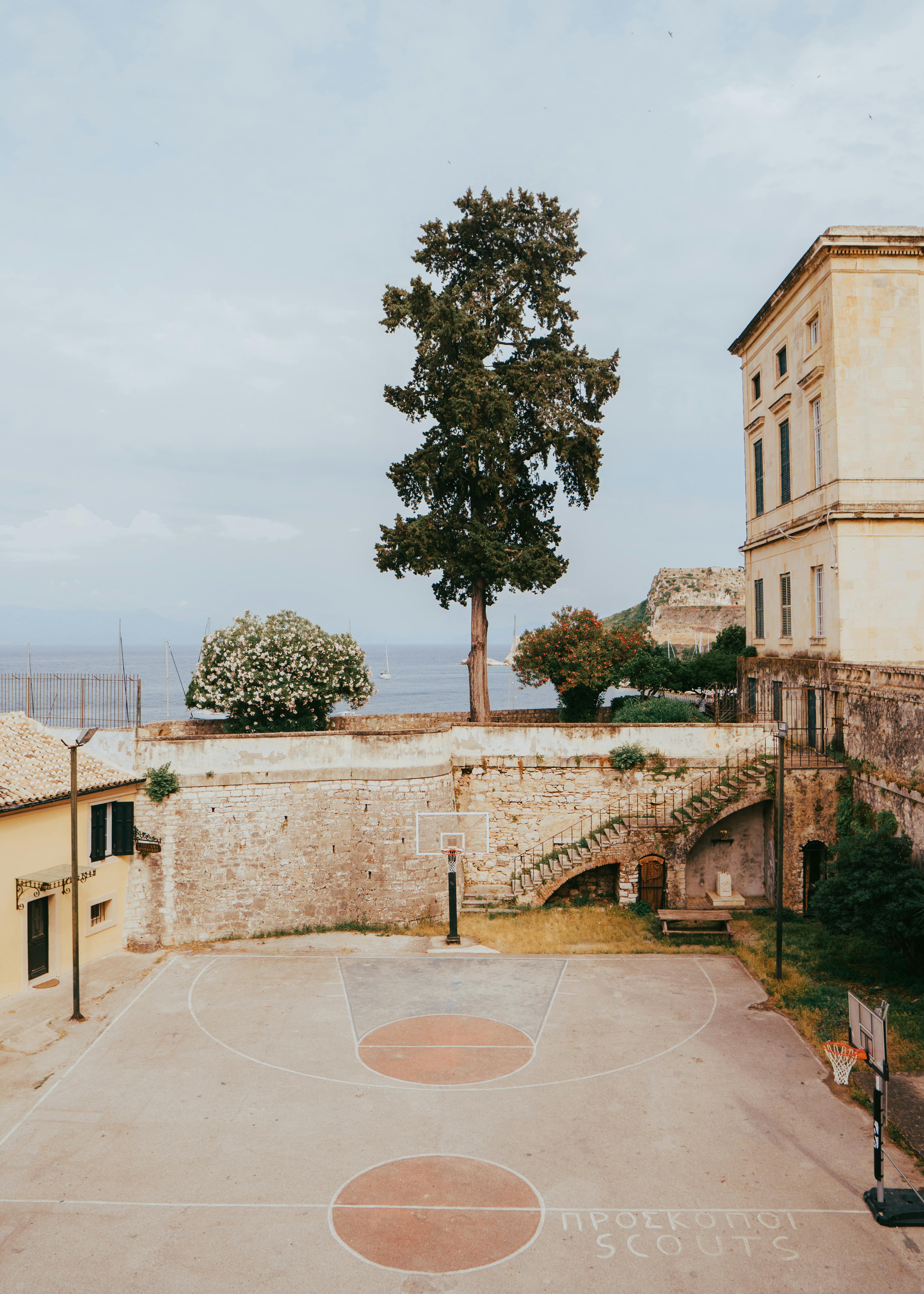 A scenic basketball court in Kerkyra, surrounded by stone walls and historic architecture.
