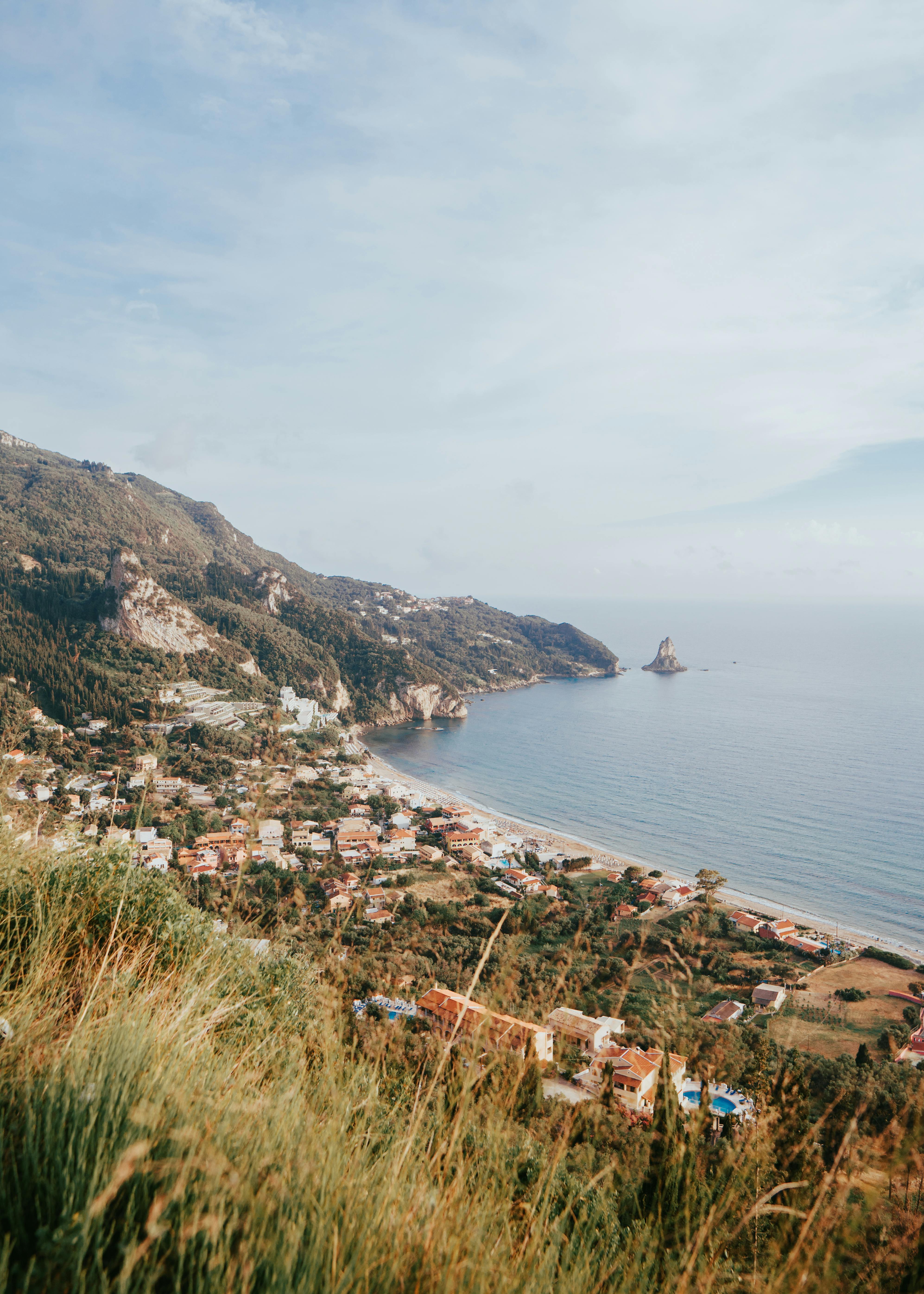 Beautiful coastal town of Kerkyra, Greece with lush green hills and blue sea.
