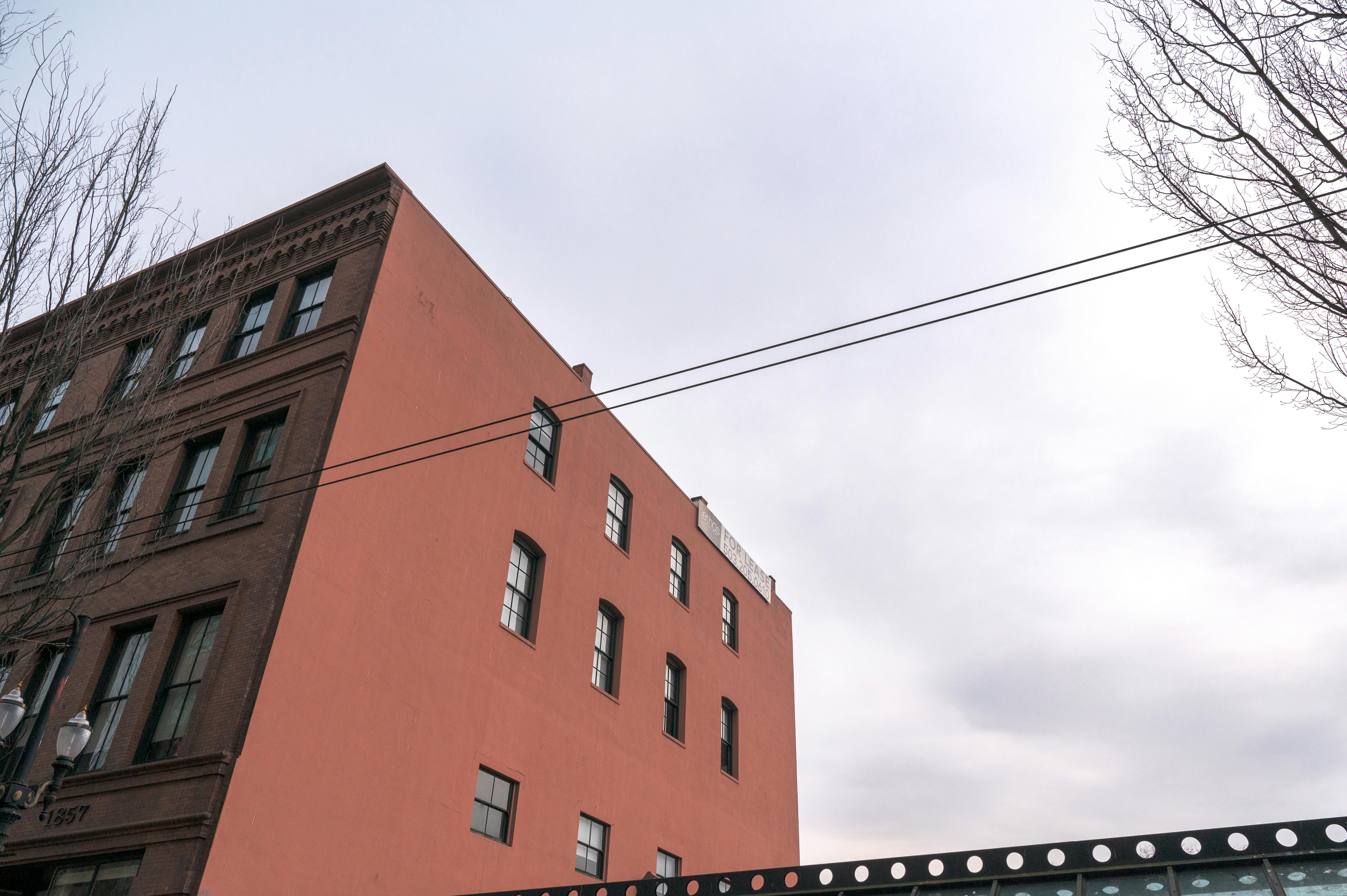 Red brick townhouse against cloudy sky, showcasing urban architecture.