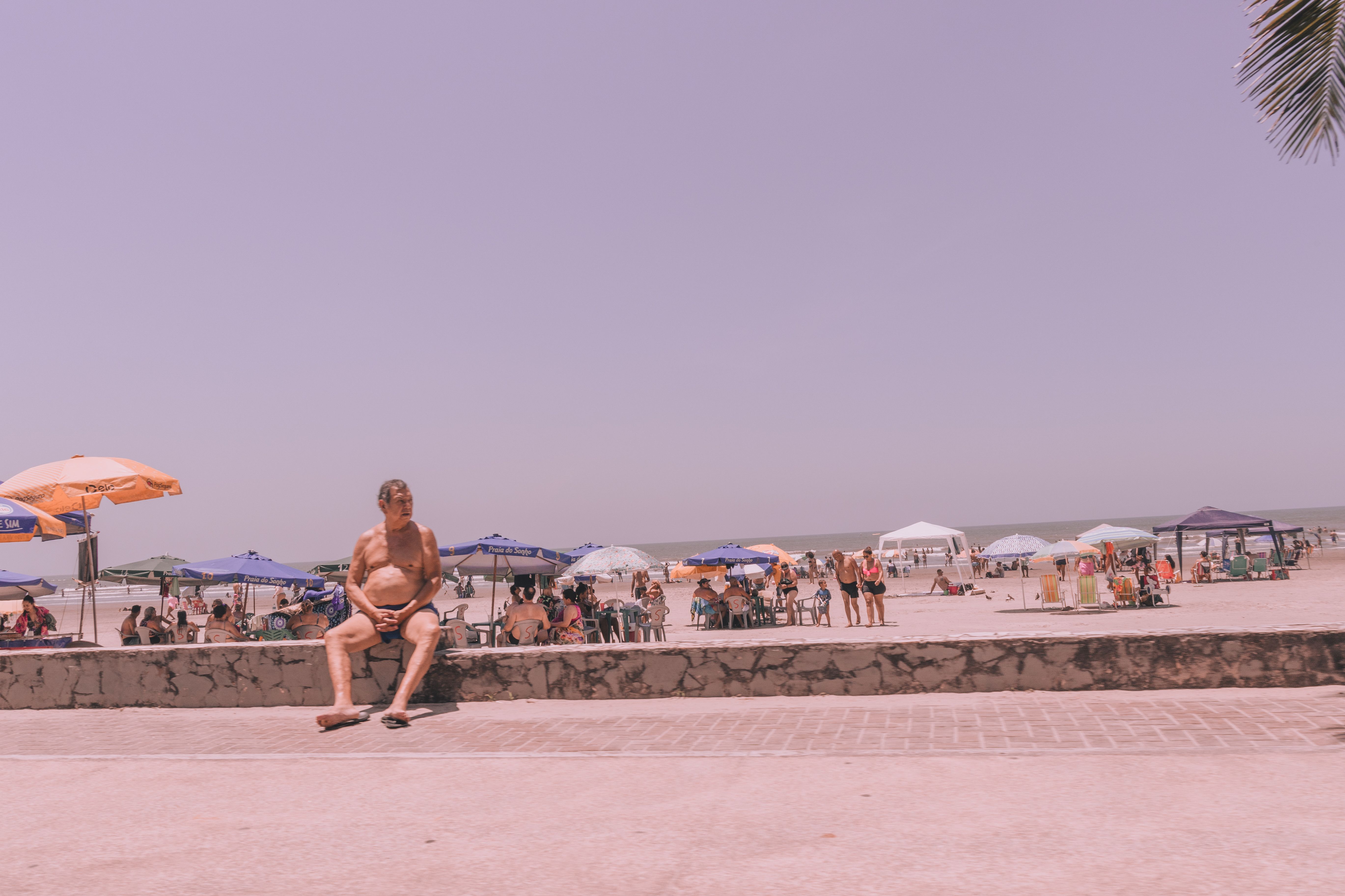 Elderly man enjoys a sunny day at the beach. Perfect vacation scene with umbrellas and sand.