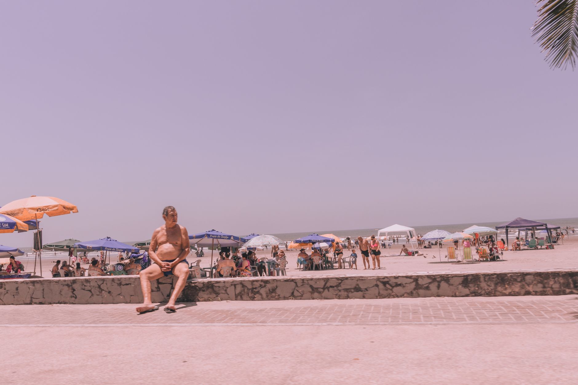 Elderly man enjoys a sunny day at the beach. Perfect vacation scene with umbrellas and sand.
