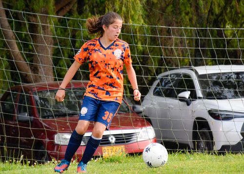 Free Teenage girl in sportswear playing soccer on a grassy field outdoors. Action and motion. Stock Photo