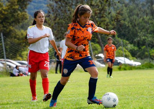 Free Girls playing soccer on a grassy field during a friendly match, showcasing teamwork and skill. Stock Photo