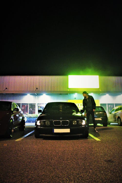 Photo of Man Standing Beside Black BMW Car