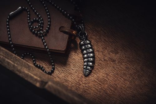 Free Close-up of a metal pendant necklace on a wooden surface, showcasing elegance. Stock Photo