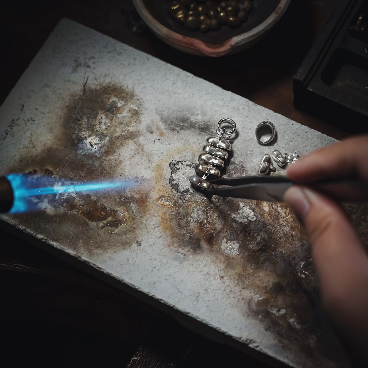 Artisan working with silver and flame to craft handmade filigree jewelry, representing Cuttack's Tarakasi silver craft