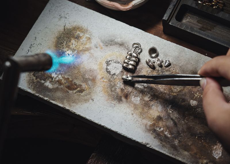 Silversmith directing a torch flame onto a piece at the bench — photo by COPPERTIST WU on Pexels