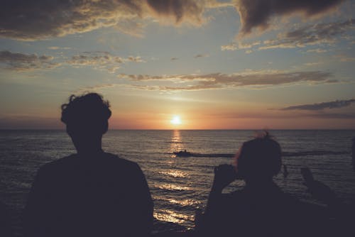 Silhouette of Woman and Man on Shore at Sunset