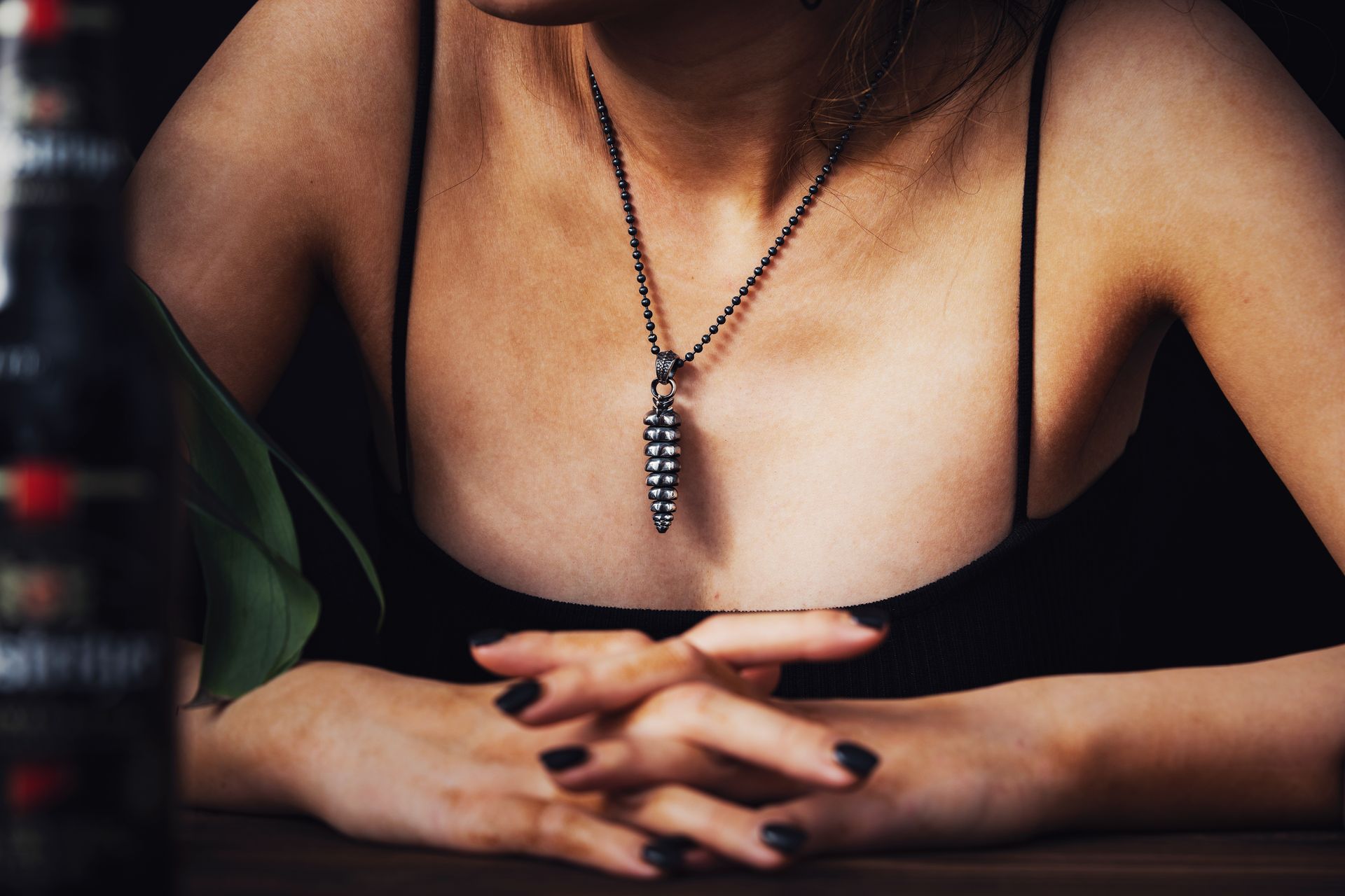 Close-up of a woman showcasing a rattlesnake tail pendant necklace, embracing elegant accessory fashion.