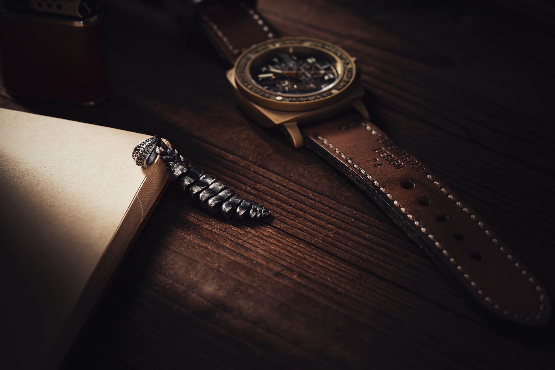 Close-up of an elegant watch and rattlesnake pendant on a wooden desk, capturing luxury and style.
