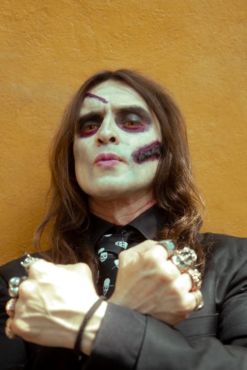 Free Man with scary Halloween makeup and fake scars poses against an orange background. Stock Photo