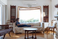 一个女人舒适地躺在阳光明媚的客厅沙发上，在笔记本电脑上工作