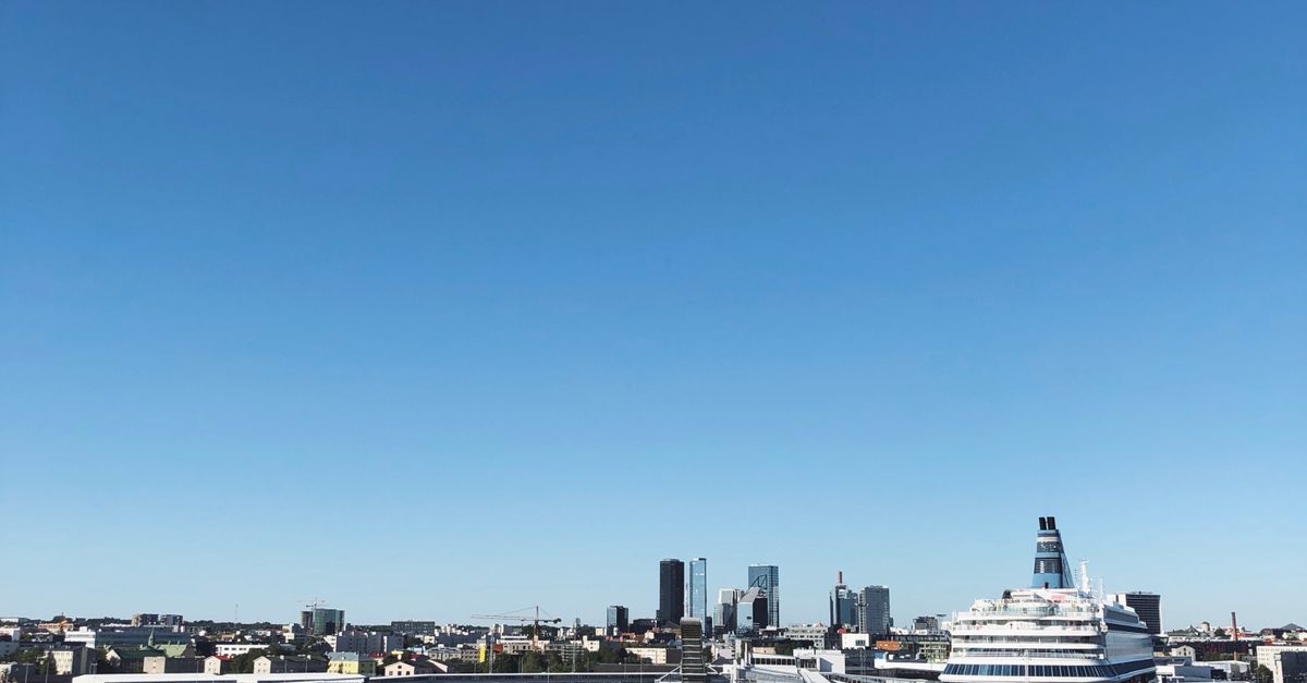 A beautiful cruise ship docked at a city harbor, with urban cityscape in the background.