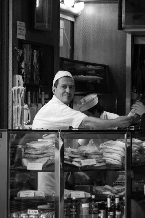 Free A friendly baker smiles while preparing goods in a cozy bakery display. Stock Photo