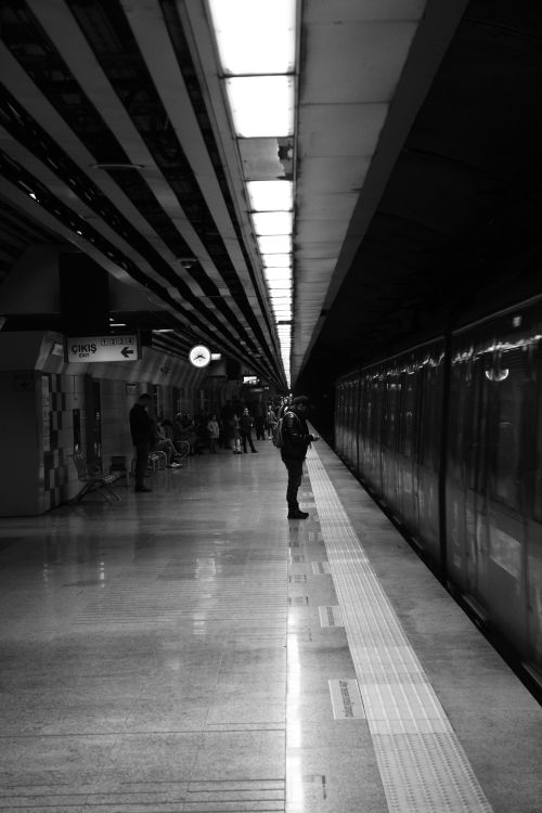 Free A black and white view of a person at an İstanbul metro station platform, showcasing symmetry. Stock Photo