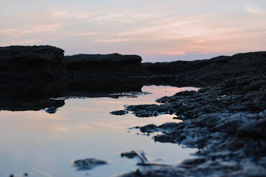 夕阳的余晖映照在嶙峋岩石间的水面上，营造出一片宁静的景色