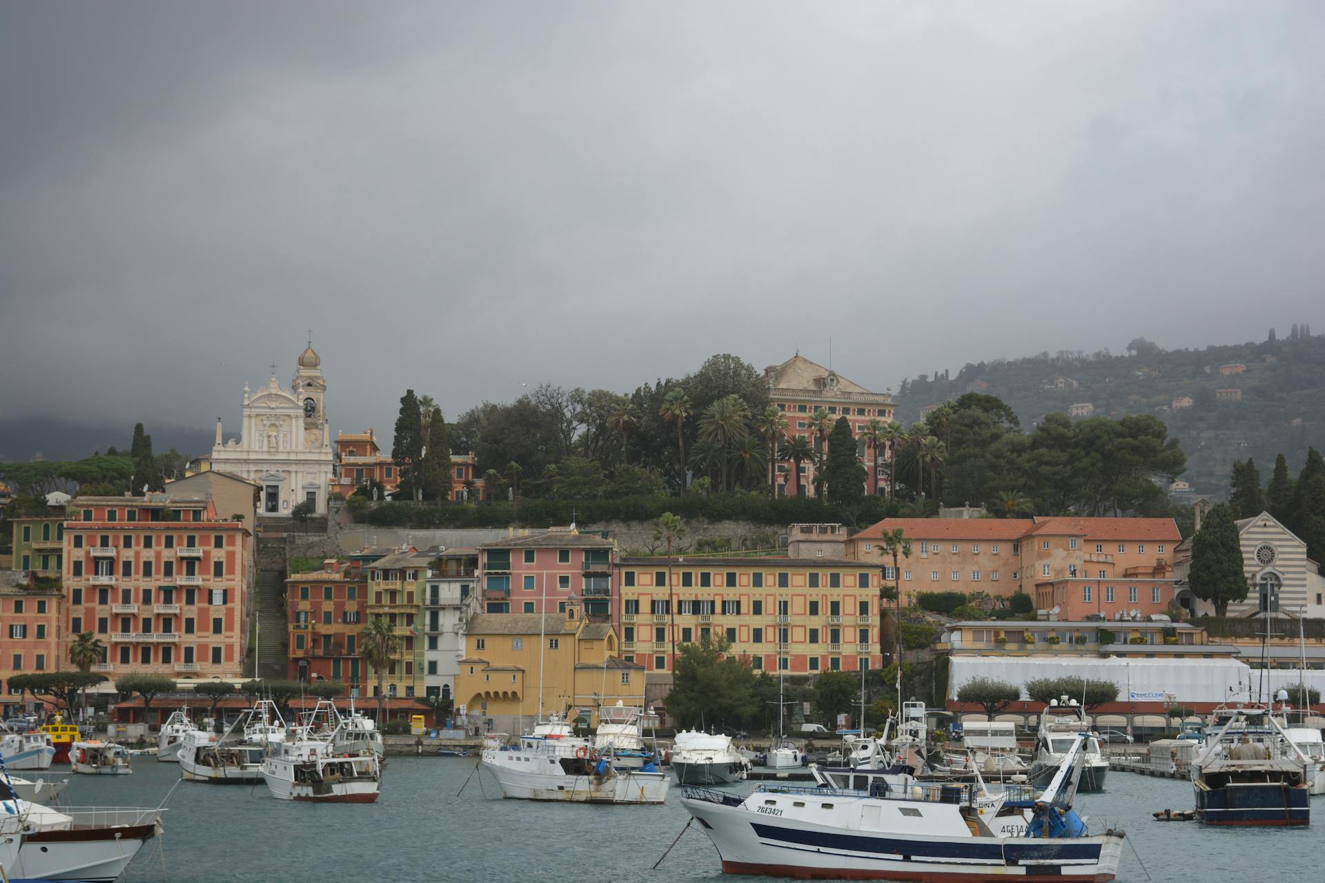 Scenic view of an Italian harbor town with boats and vibrant buildings on a cloudy day.