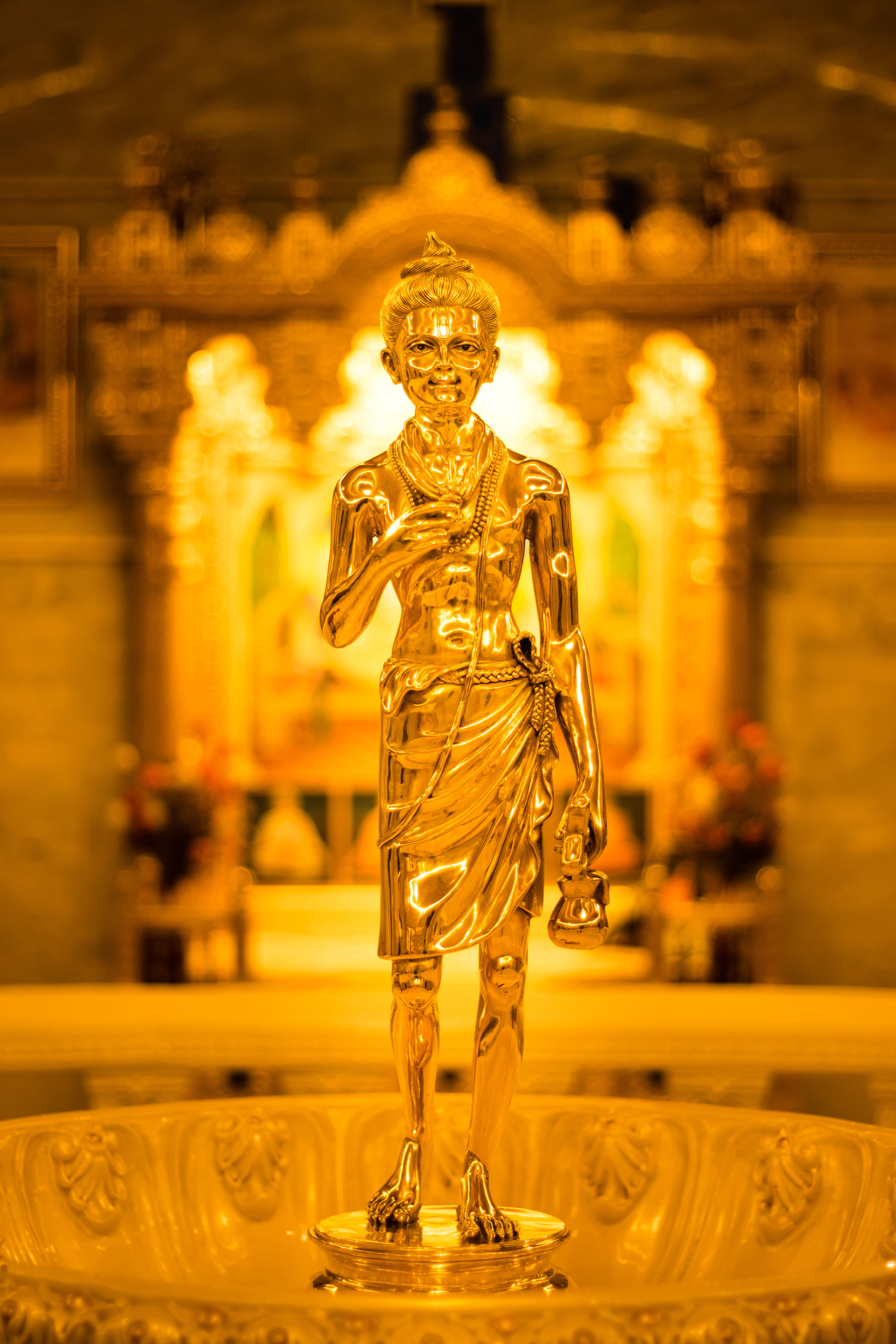 Close-up of an intricate golden statue in an Indian temple with a warm, glowing ambiance.