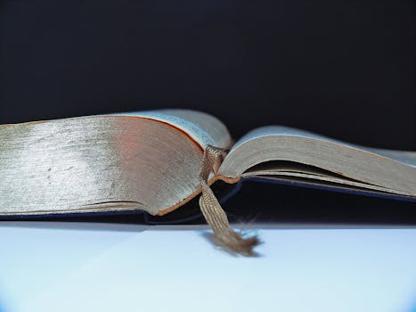 Detailed view of an open book with a brown bookmark set against a dark background.
