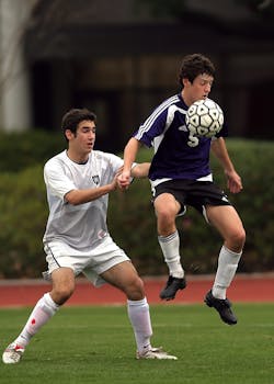 两名青少年参加了一场注重技巧与策略的激烈户外足球比赛