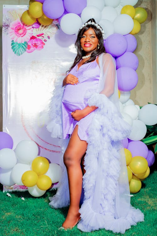 Pregnant Woman in a Dress Standing on the Background of a Wall with Balloons 