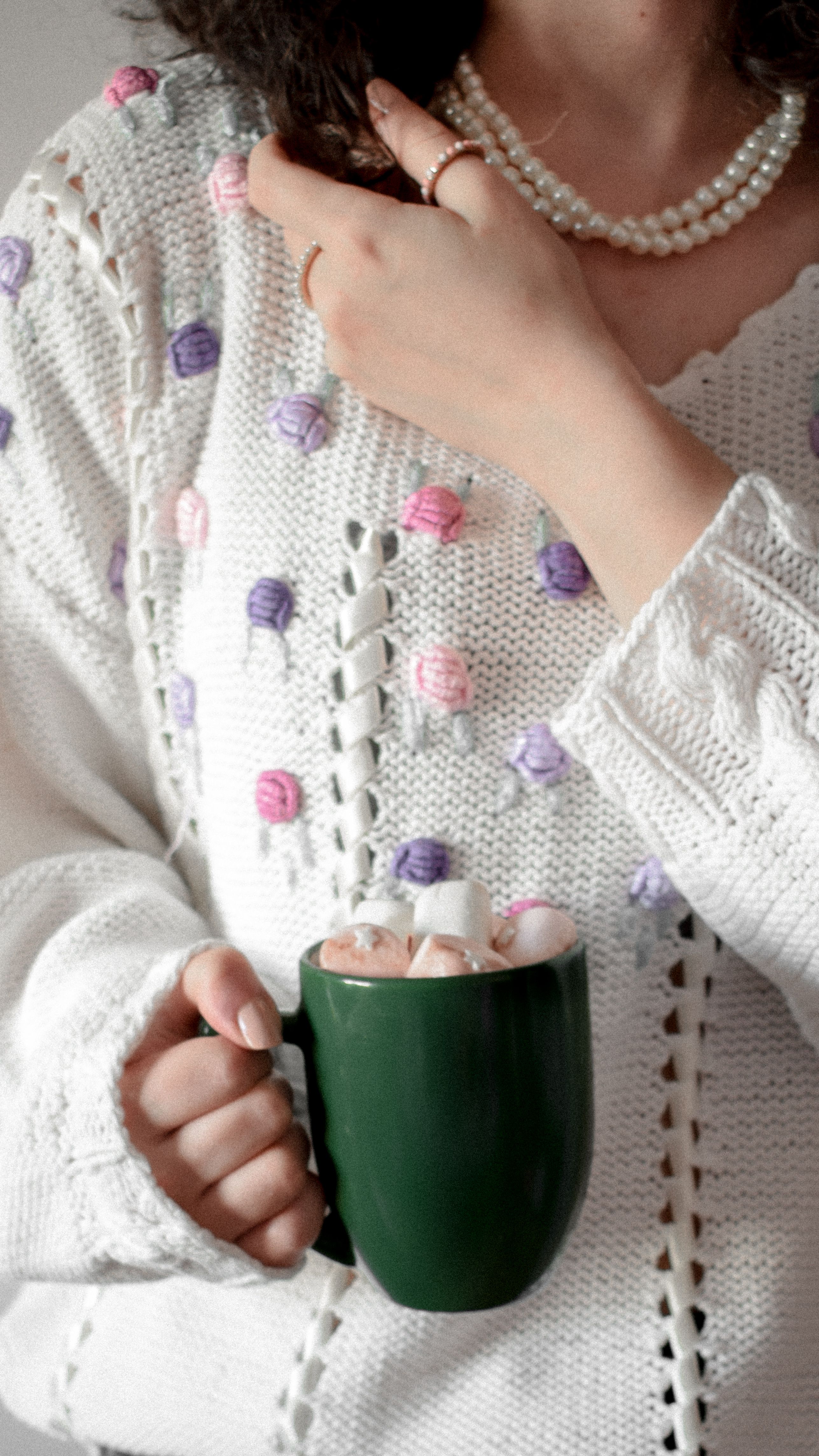A woman holding a coffee cup and wearing a sweater · Free Stock Photo