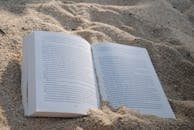 一本在沙滩上打开的书，象征着放松和休闲阅读