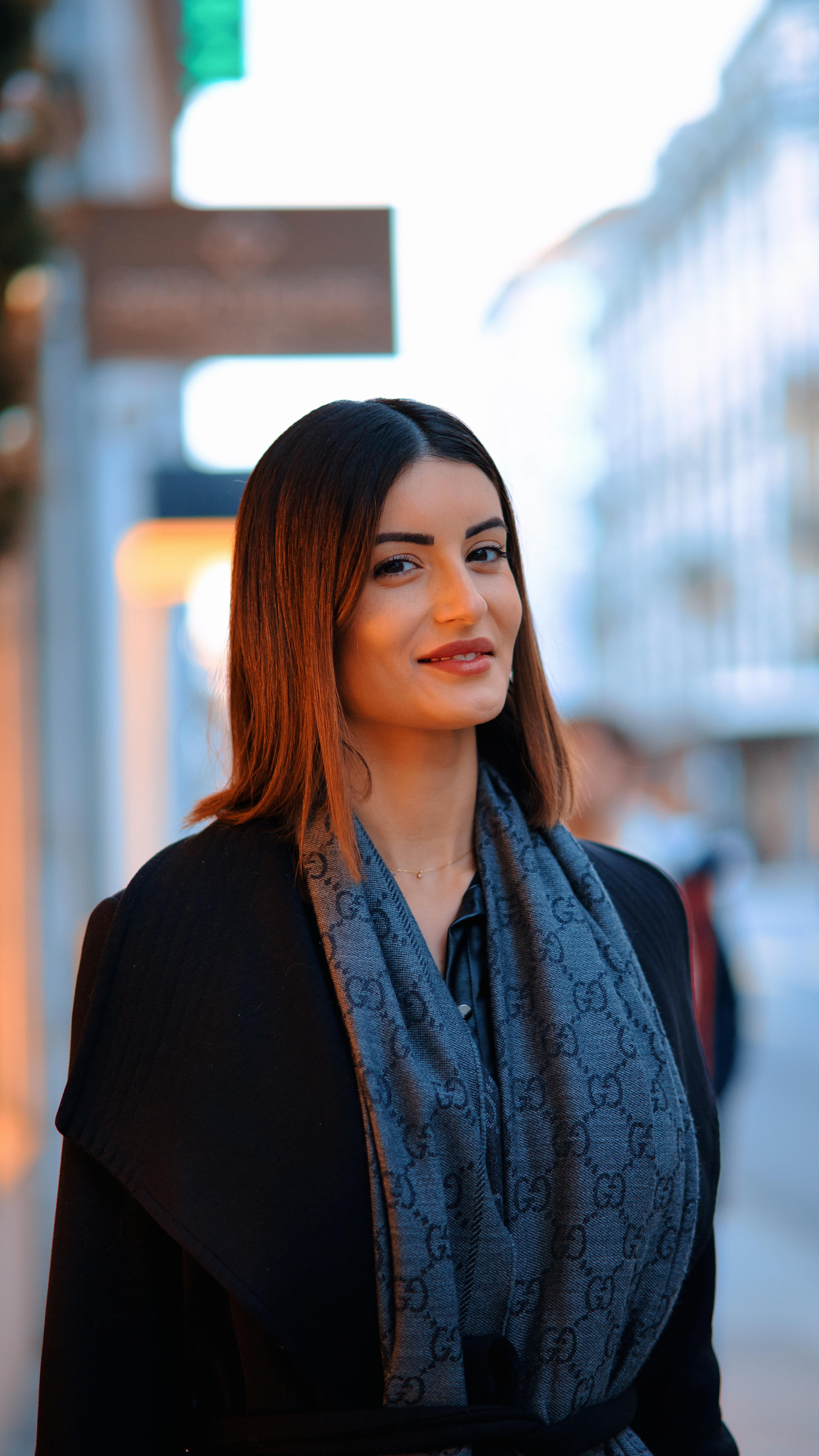 Elegant woman with scarf strolling in a city street during the day.