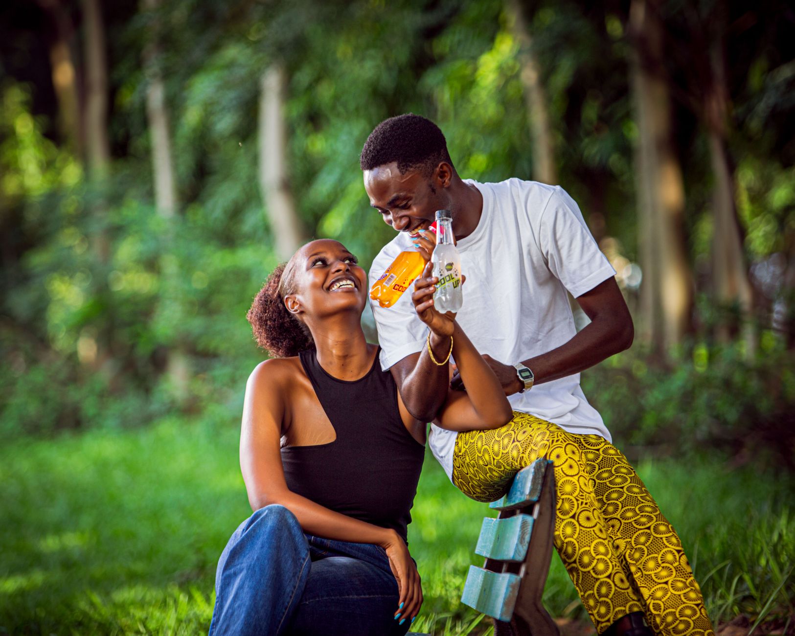 Happy couple laughing and enjoying drinks together in a vibrant outdoor setting, creating a lively and fun atmosphere.
