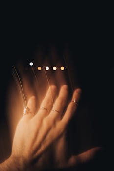 Blurred hand wearing rings with artistic light trails against a dark background.