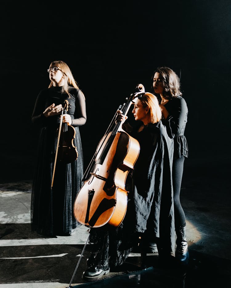 Women In Black Dresses, Playing A Cello And A Violin, Performing On Stage 