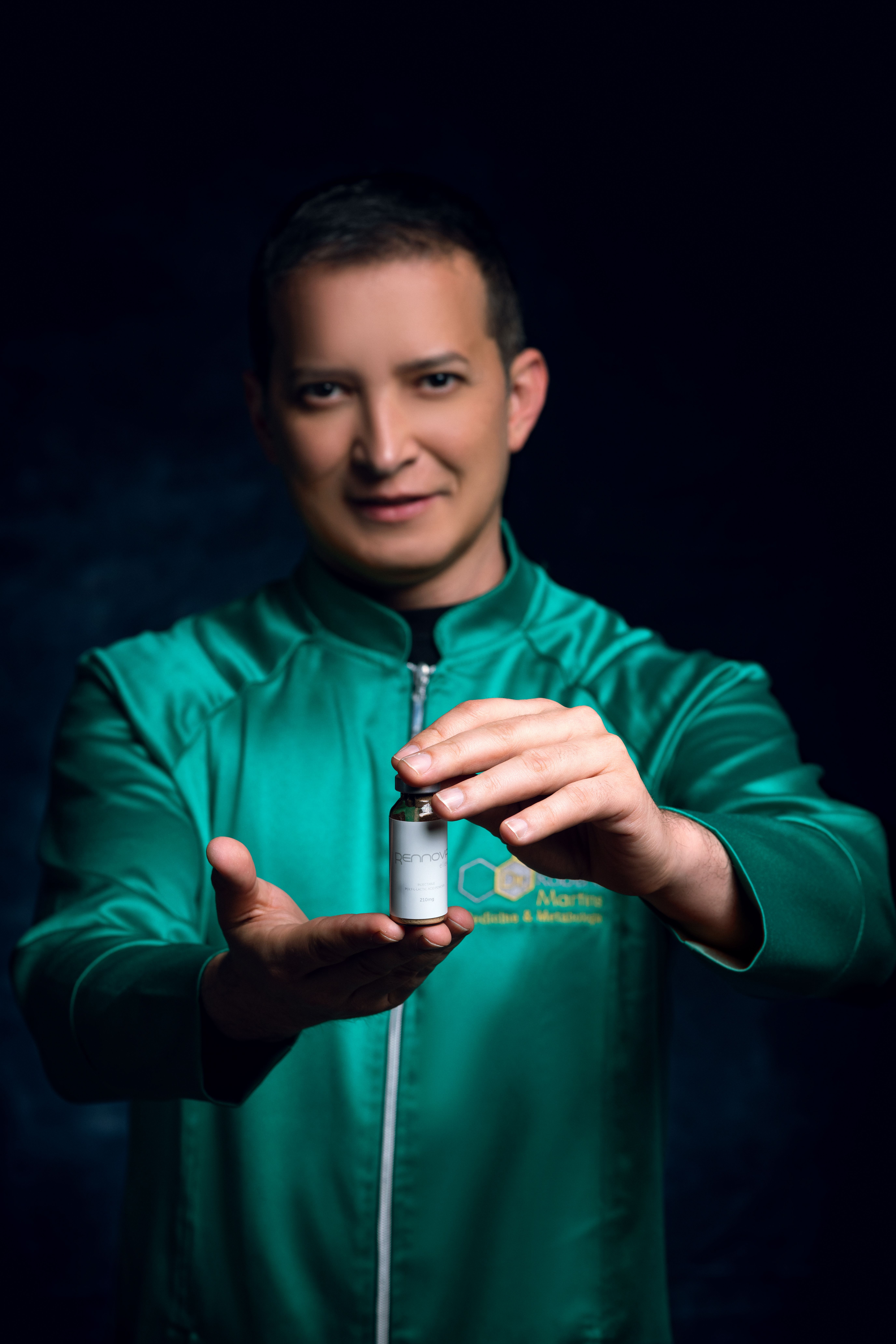 Portrait of a man in a green jacket holding a vial, isolated on black background.