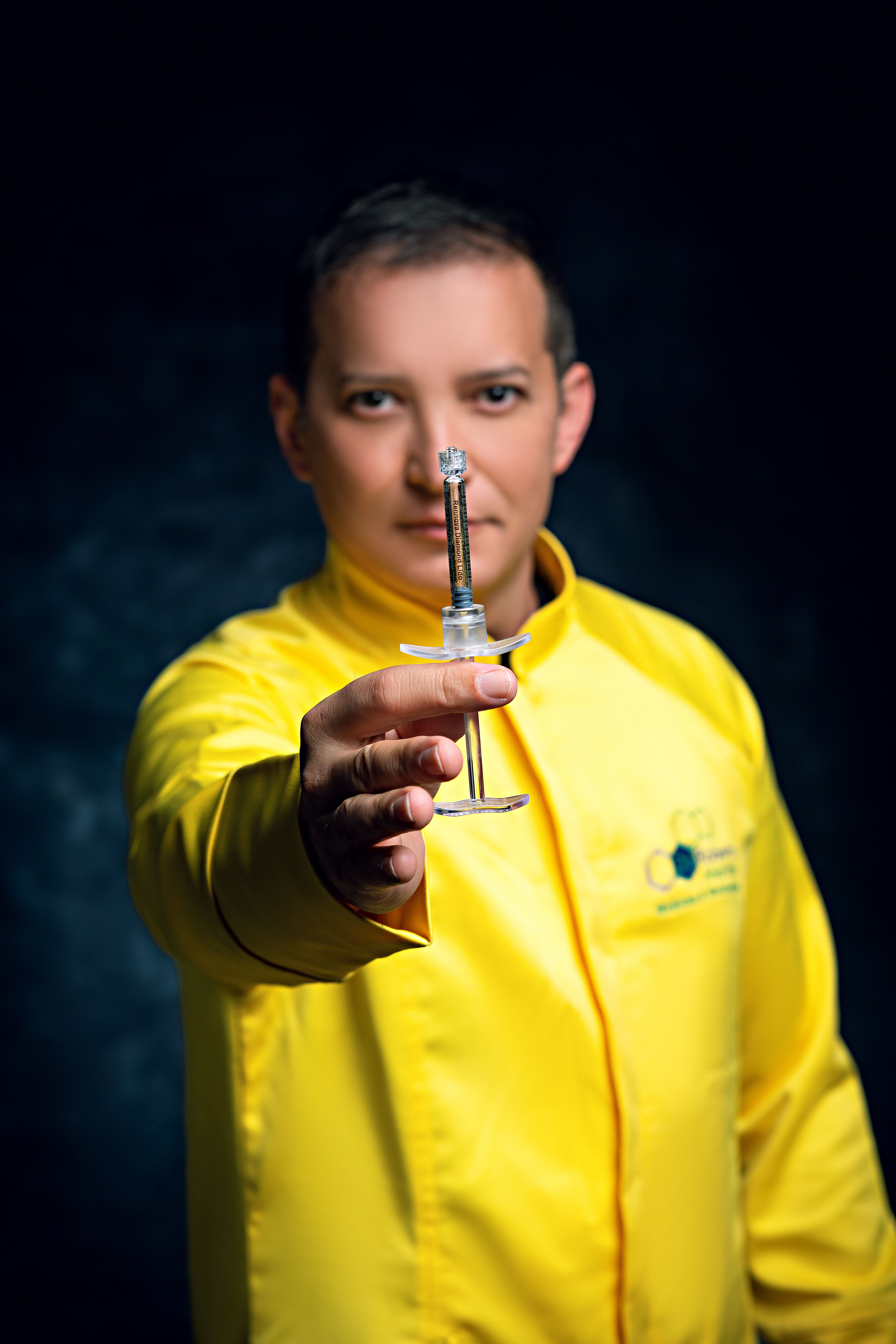 Close-up of a man in a yellow jacket holding a syringe, emphasizing medical themes.